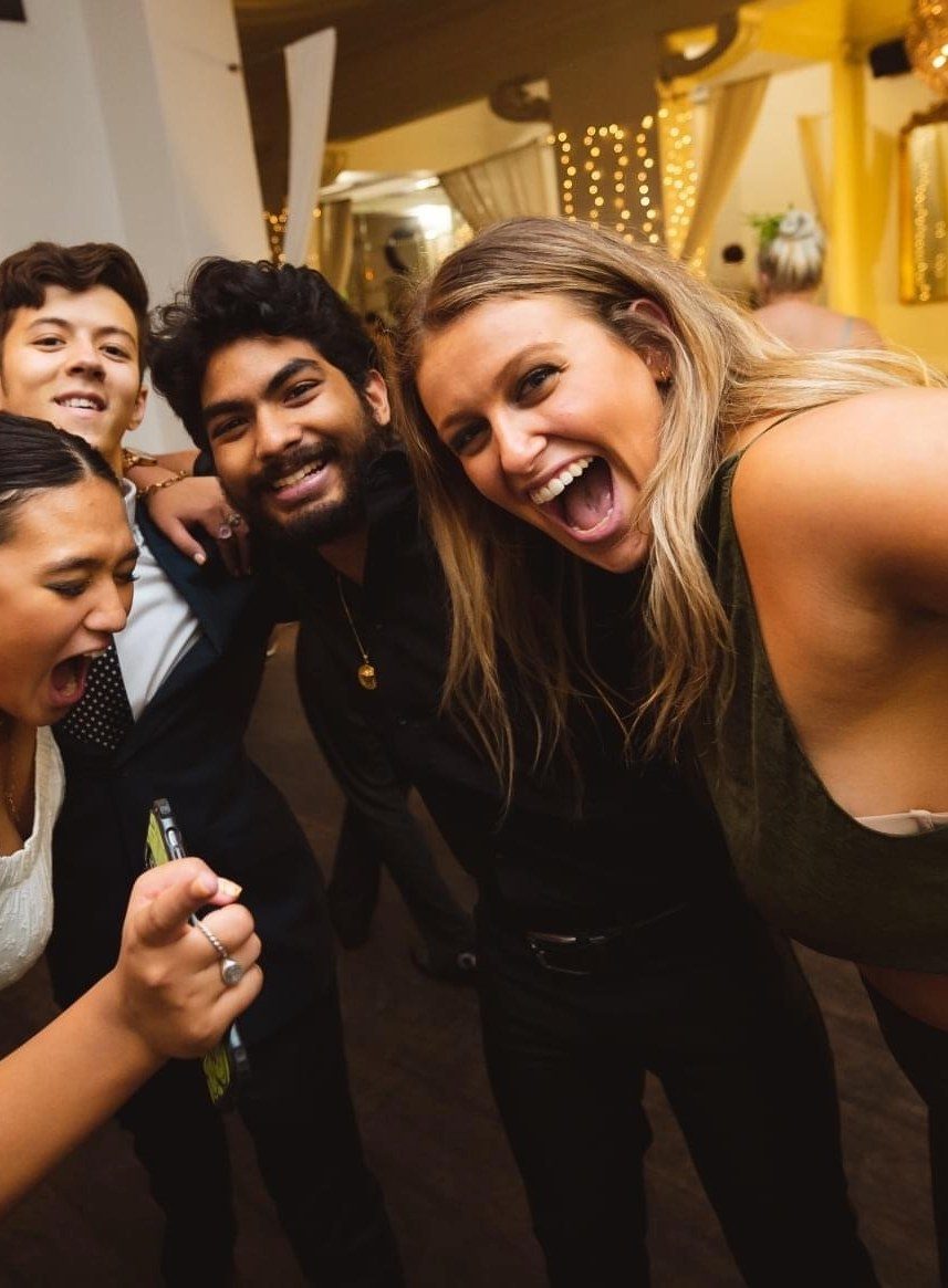 Friends squeeze in for a dance-floor selfie, laughing